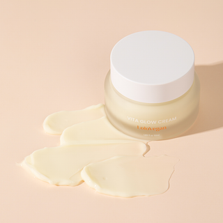 Jar of Vita Glow Cream with cream spread on a beige background